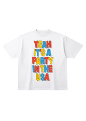 White t-shirt with colorful text 'Yeah It's a Party in the USA' on a white background, flat lay frontal view