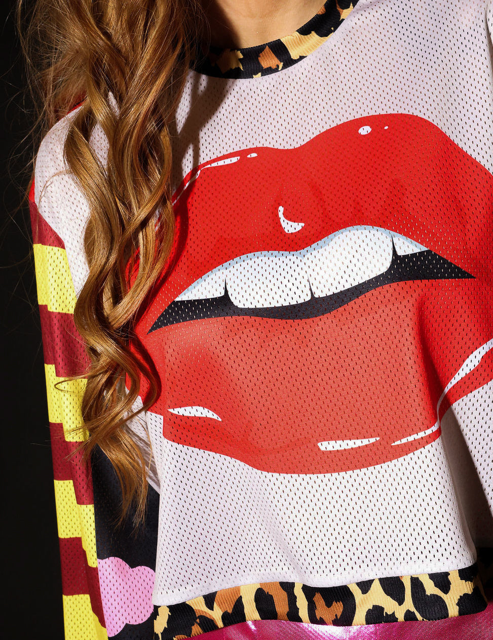 Model wearing close-up of a colorful mesh jersey with a prominent red lip design, leopard band near waist, frontal view