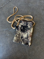 Small bag with a cat design and gold straps on a concrete background