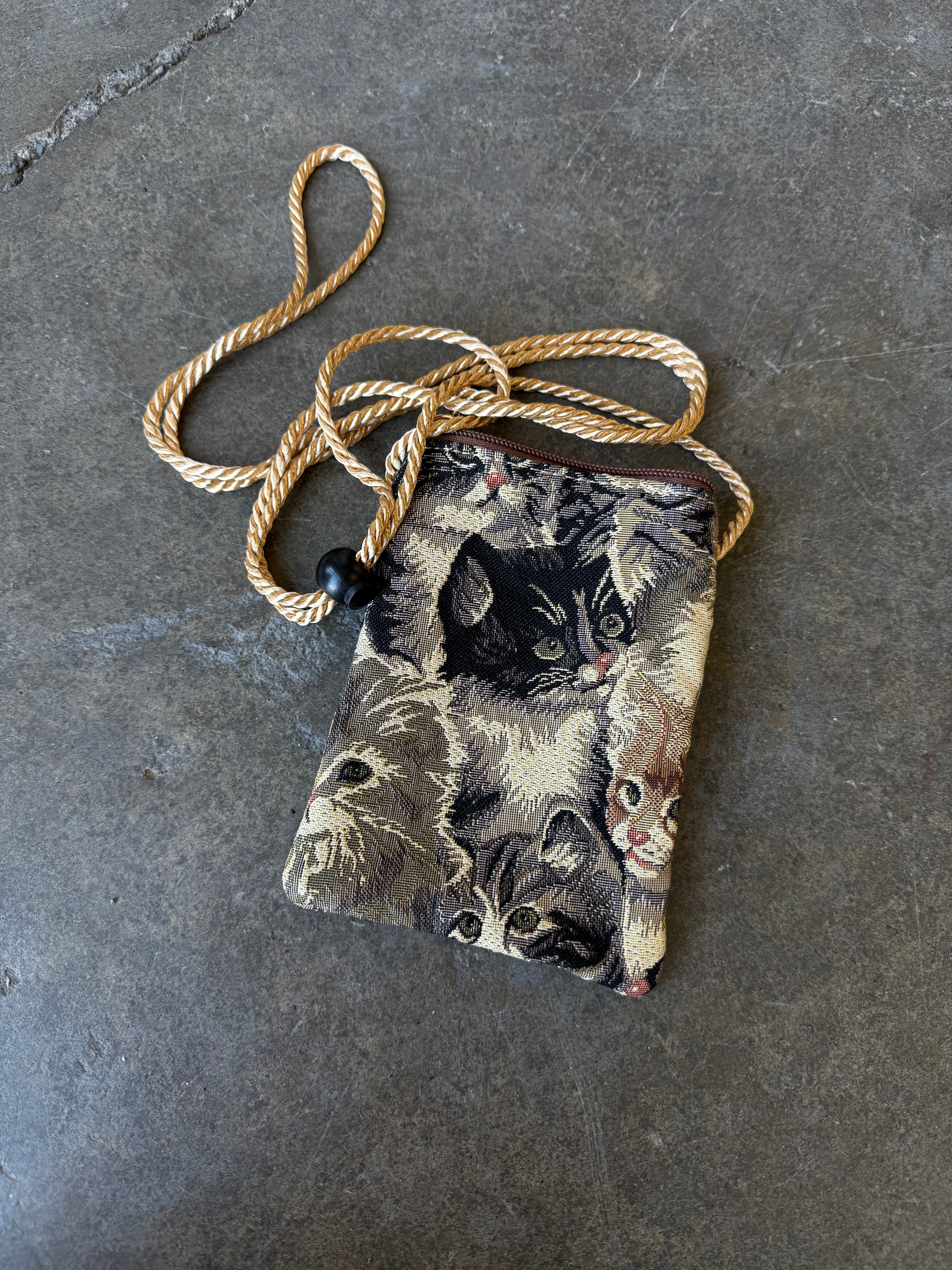 Small bag with a cat design and gold straps on a concrete background