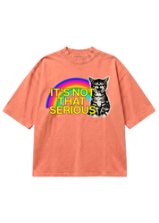 A coral pink short-sleeve t-shirt with a graphic on the front showing a black and white cat next to a rainbow and the text 'IT'S NOT THAT SERIOUS' in yellow.