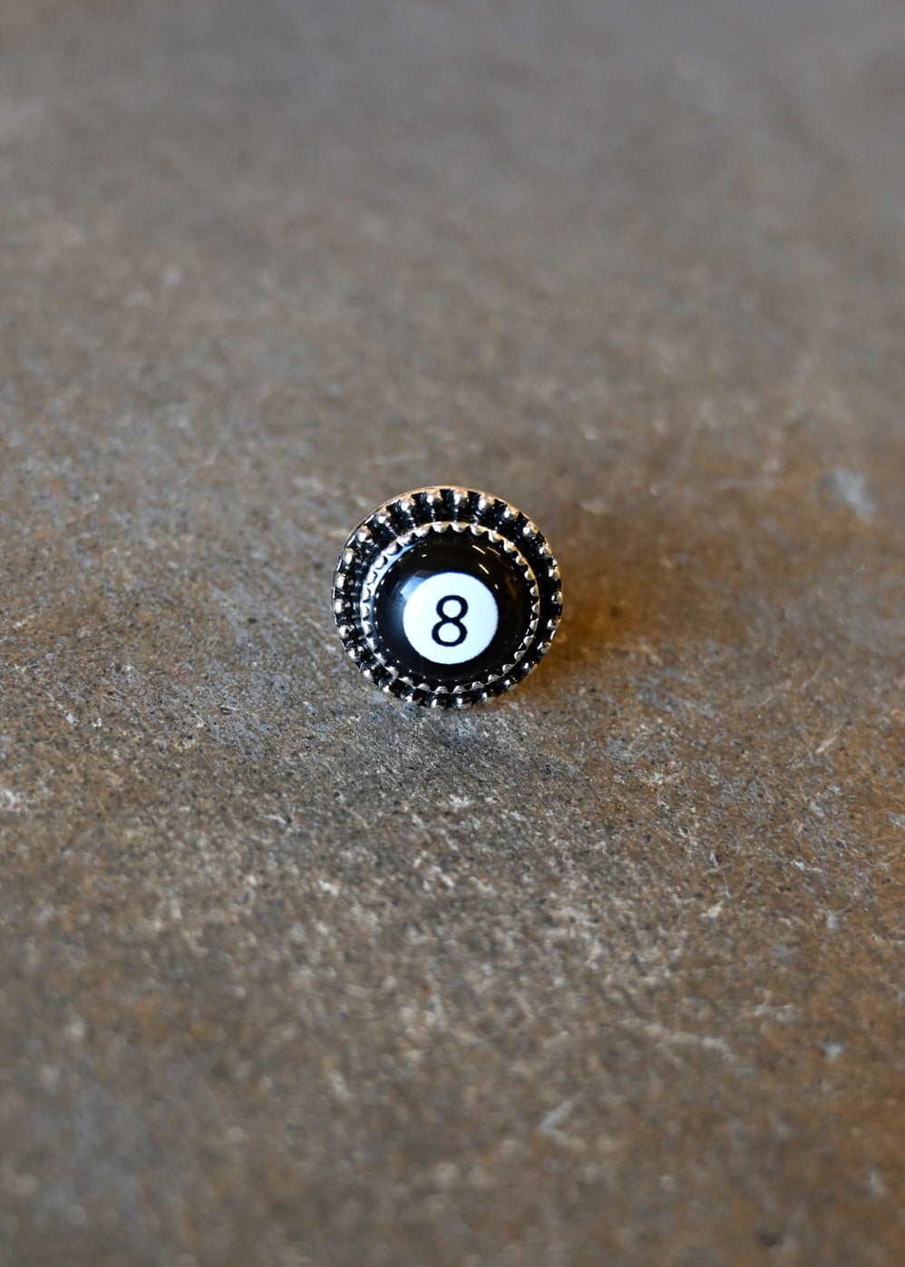 A silver ring with an 8 ball pendant on a dark background
