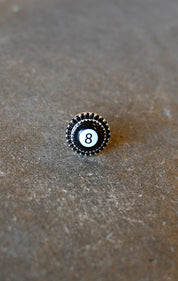 A silver ring with an 8 ball pendant on a dark background