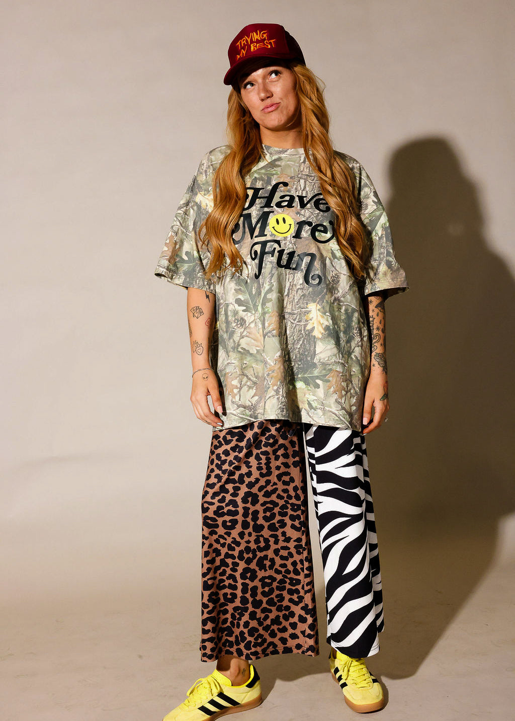 Model is wearing a camo graphic shirt, half leopard print pants, half zebra print pants on a beige background, frontal view