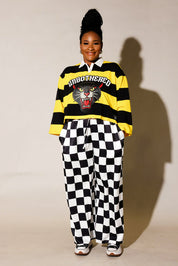 Model wearing a black and yellow striped polo, and black and white checkered pants, frontal view
