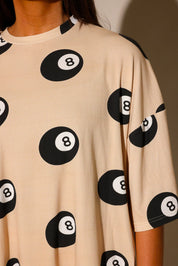 Model wearing ribbed short sleeve shirt with black 8 balls throughout, against a plain background, highlighting collar, frontal view