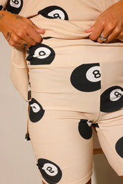 Model wearing a beige ribber biker short,with black 8 balls throughout, against a plain background, close up frontal view of shorts