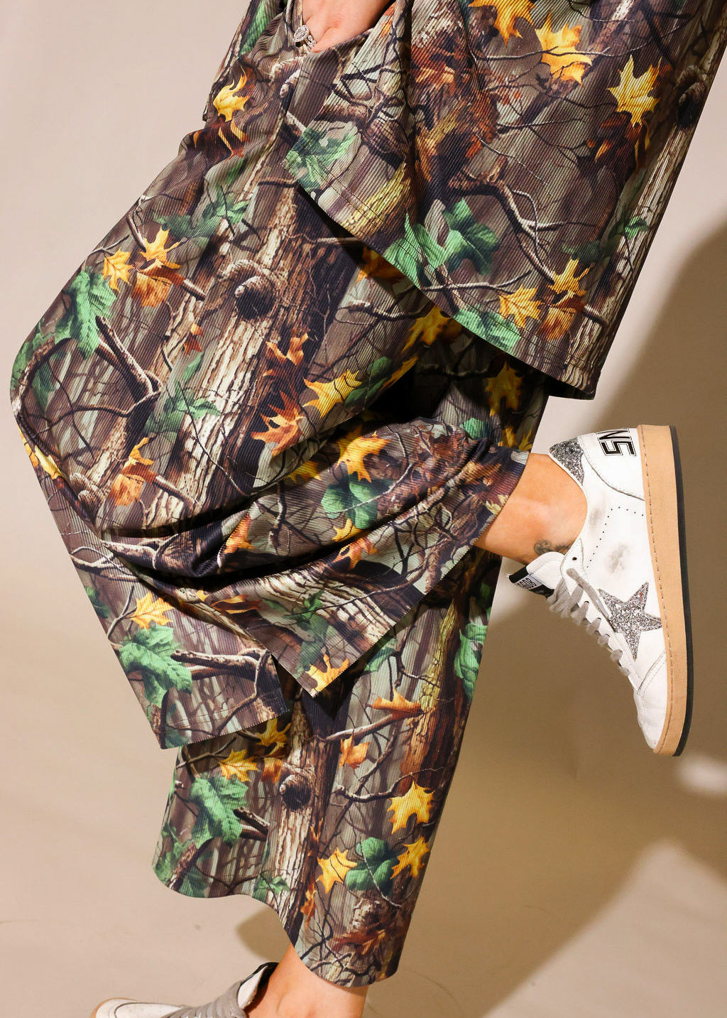 Model wearing a camouflage ribbed short sleeve and pant set, on a beige background, close up side view