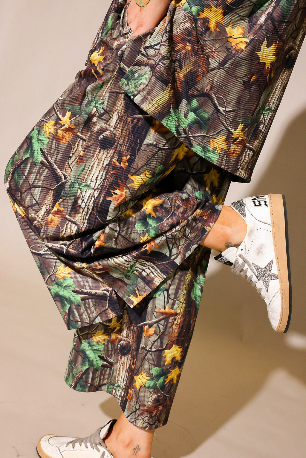Model wearing a camouflage ribbed short sleeve and pant set, on a beige background, close up side view