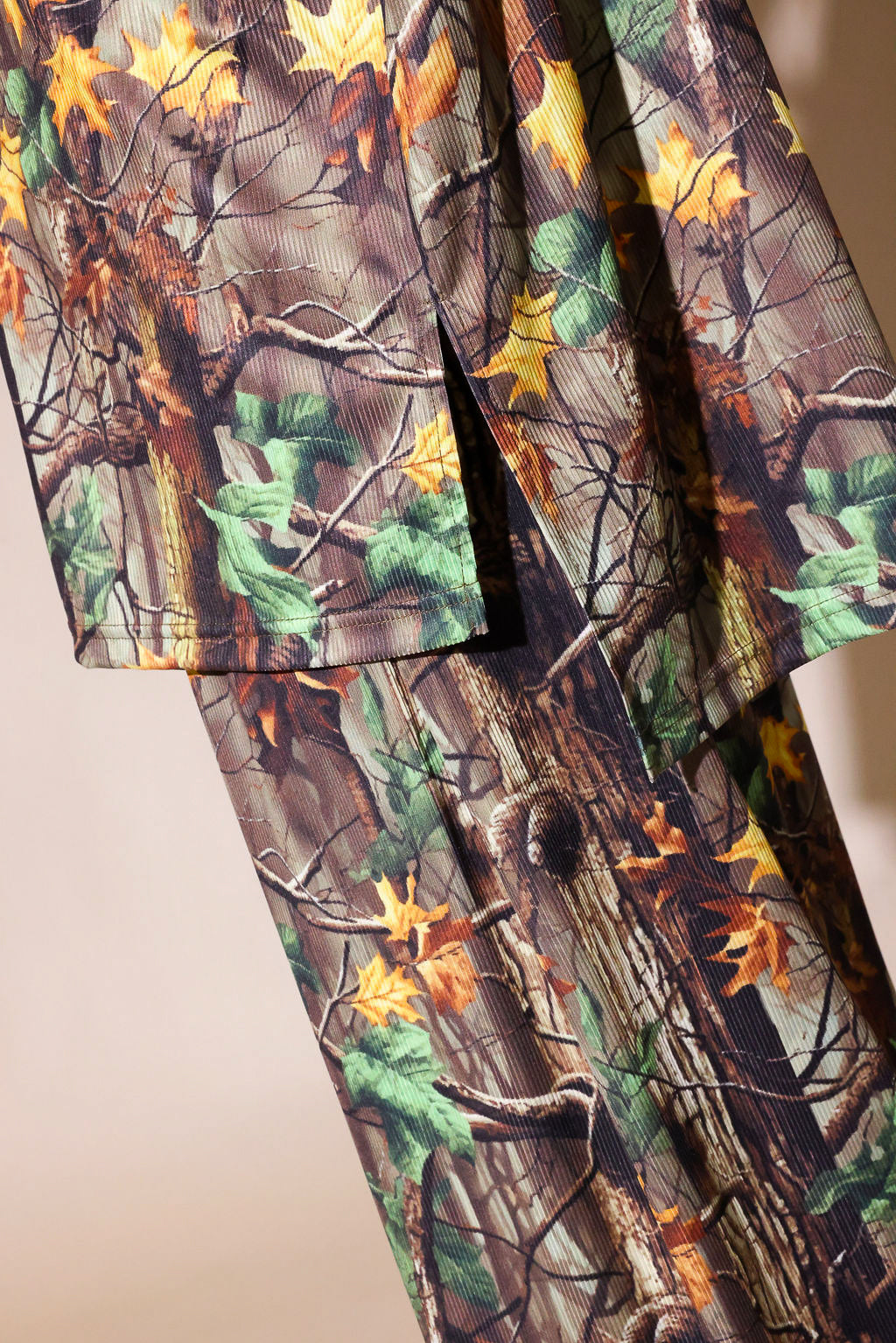 Camouflage patterned fabric with tree and leaf design on a plain background, side view