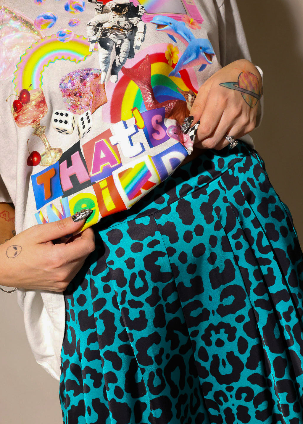 Model wearing color graphic tee shirt, and blue and black leopard satin pants, highlighting waist details, close up frontal view