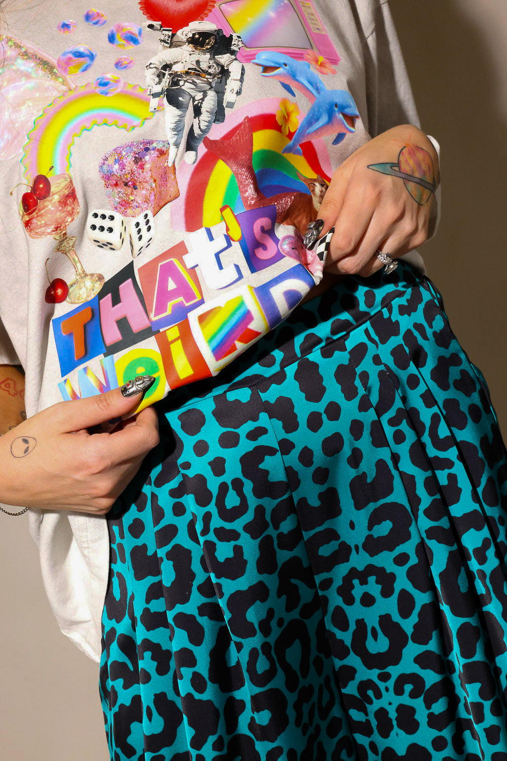 Model wearing color graphic tee shirt, and blue and black leopard satin pants, highlighting waist details, close up frontal view