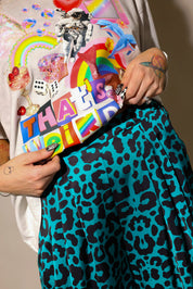 Model wearing color graphic tee shirt, and blue and black leopard satin pants, highlighting waist details, close up frontal view