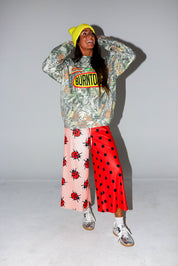 Model wearing a camo crewneck with Burnt Toast logo, red polka dot pants, and a yellow beanie, on a white background, frontal view