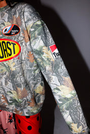 Camouflage crewneck with brand logos on a dark background, side view