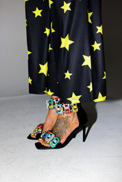 Person wearing colorful embellished heals with a star-patterned pants, close up lower half of body view