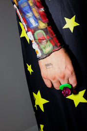 Close-up of a hand with a tattoo wearing a colorful sleeve with car toys on a dark background with yellow stars
