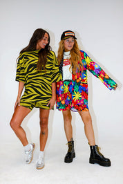 Two models, one wearing a green zebra biker set, and another wearing a colorful floral set, on a white background, frontal view