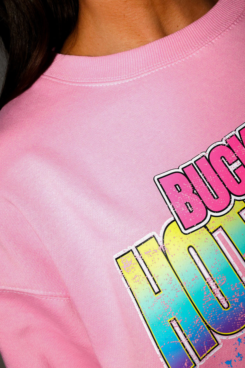 Model wearing a pink crewneck with a colorful graphic of a car and text on a plain background, close up of collar frontal view