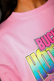 Model wearing a pink crewneck with a colorful graphic of a car and text on a plain background, close up of collar frontal view