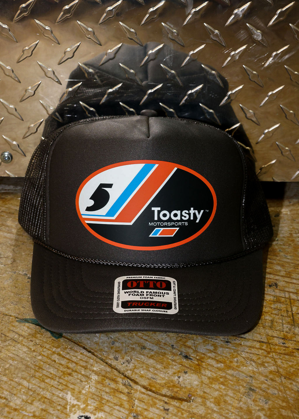 Grey trucker with a logo on a metallic surface, frontal view