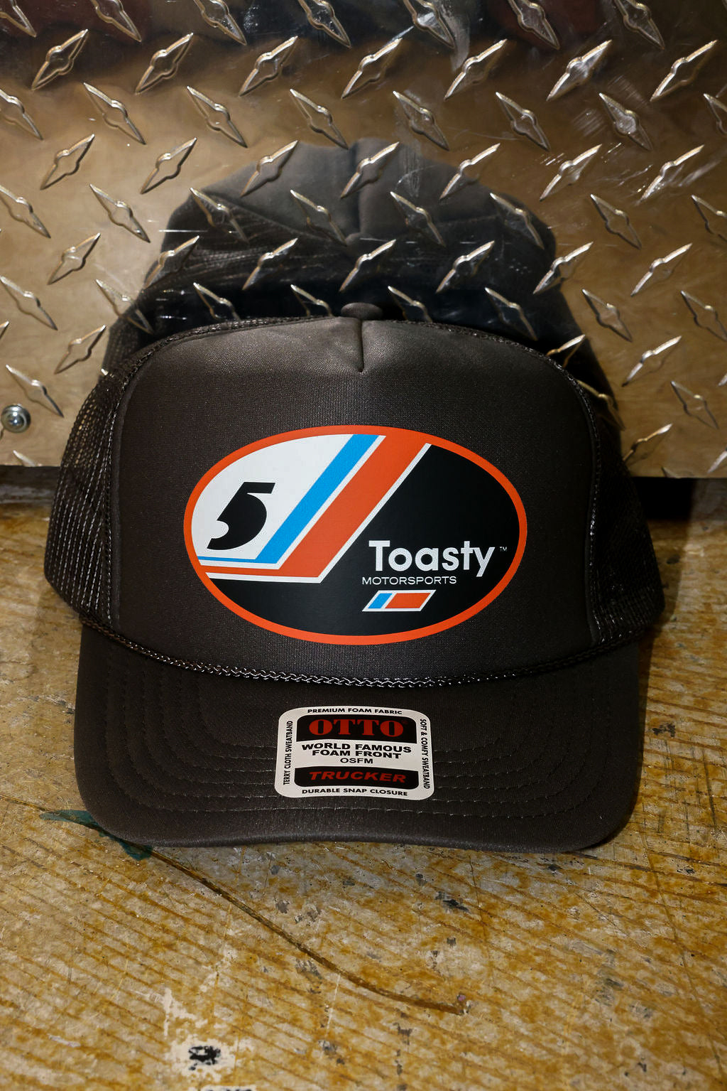Grey trucker with a logo on a metallic surface, frontal view