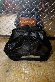 Black mesh trucker on a textured metal and wooden surface, back view