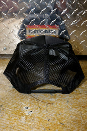 Black mesh trucker on a textured surface with a metallic background, back view