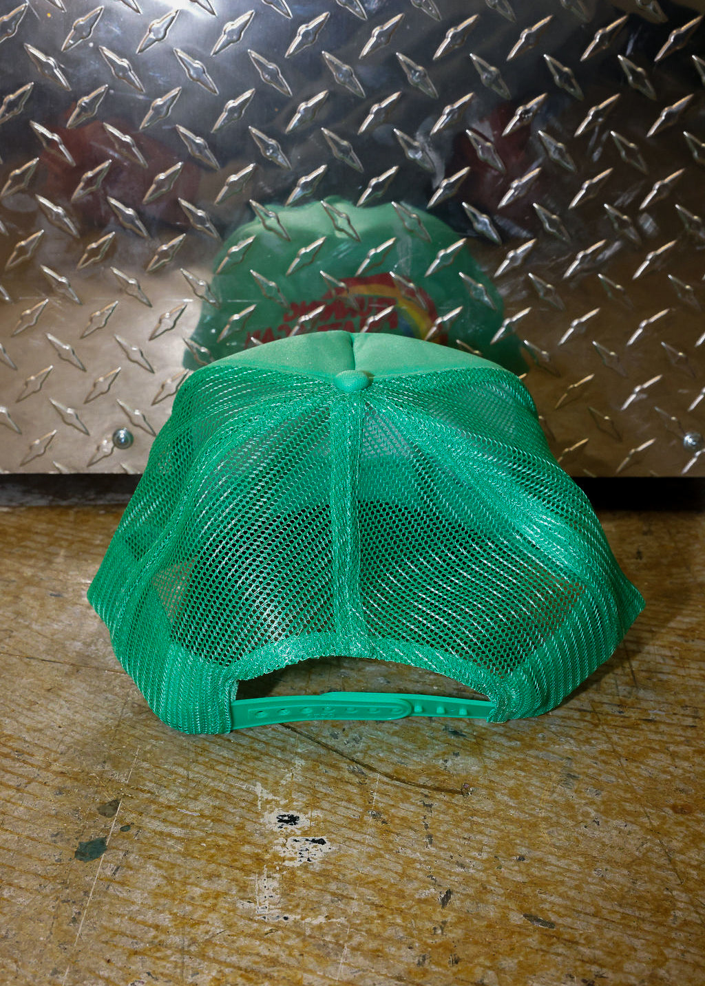 Green mesh trucker on a textured metal surface, back view