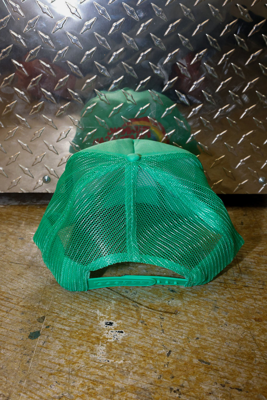 Green mesh trucker on a textured metal surface, back view