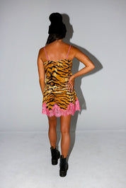 Model wearing a tiger print dress with pink lace trim on a plain backgroundm back view