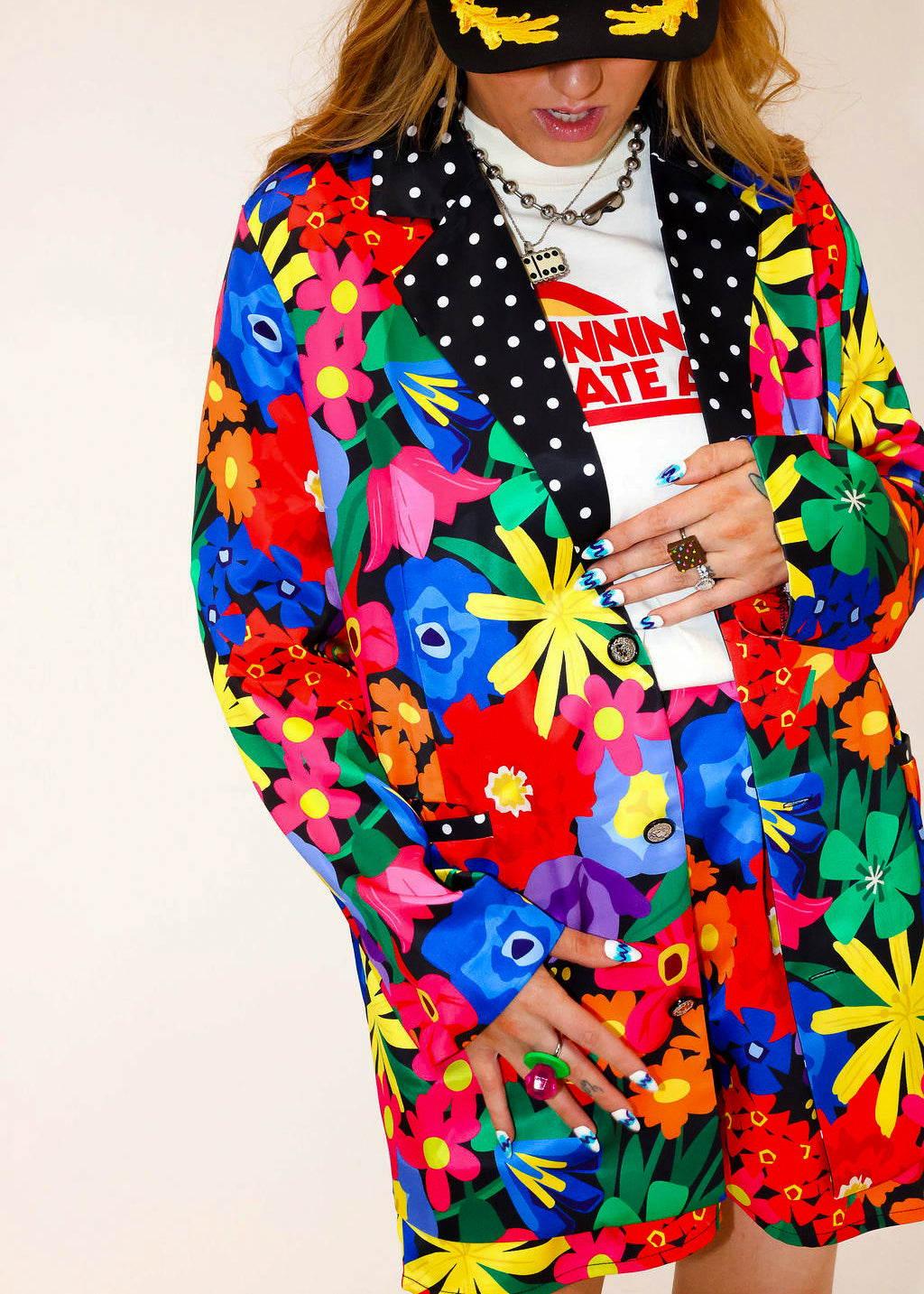 Model wearing a colorful floral jacket with polka dot collar, and matching shorts, a plain background, frontal view