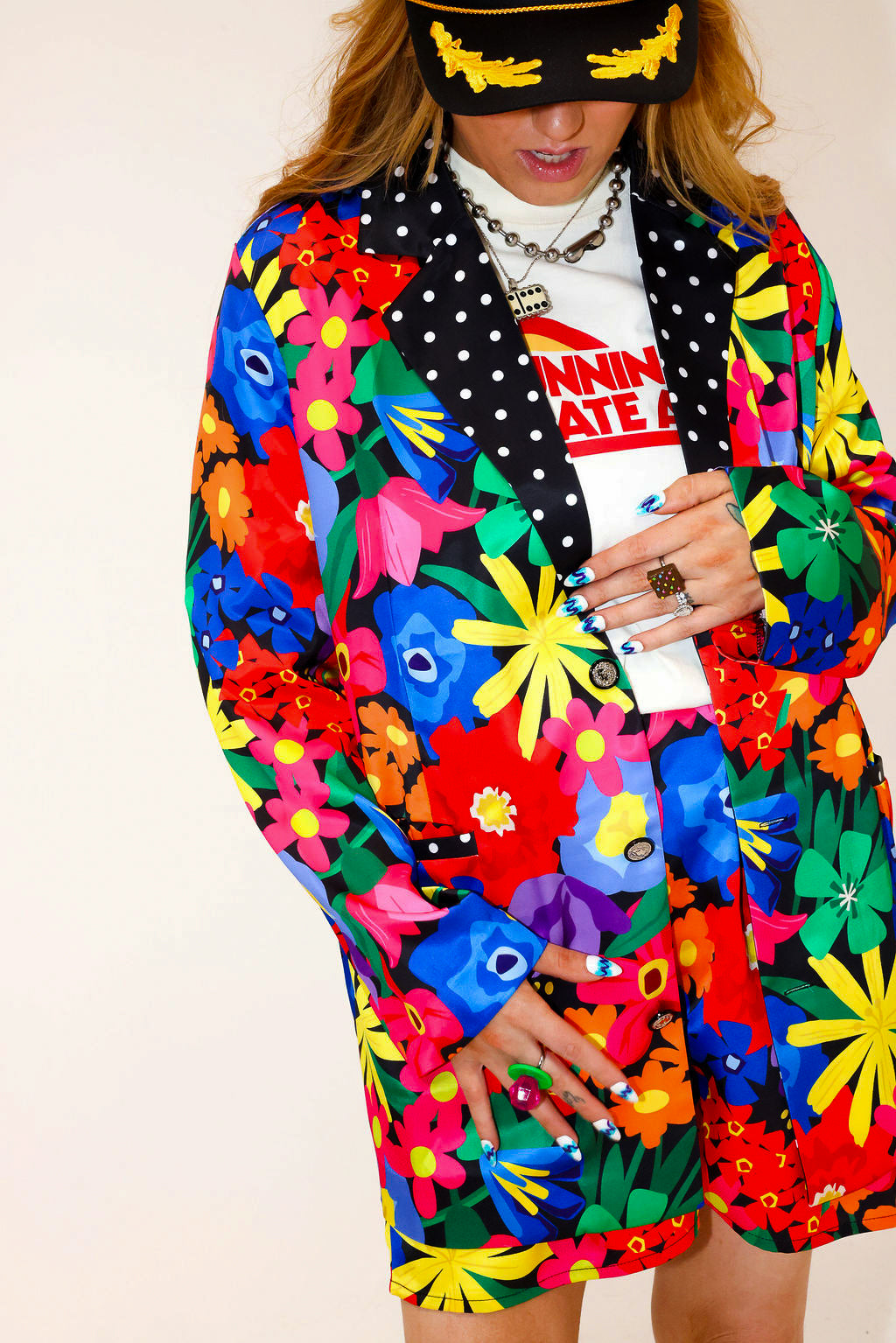 Model wearing a colorful floral jacket with polka dot collar, and matching shorts, a plain background, frontal view
