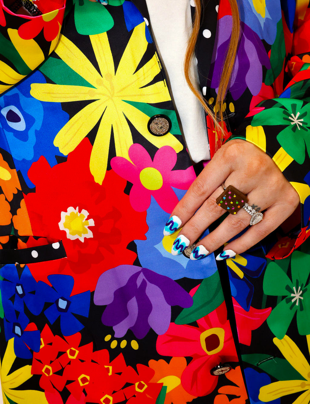 Model wearing a colorful floral jacket with polka dot collar, and matching shorts, a plain background, close up frontal view