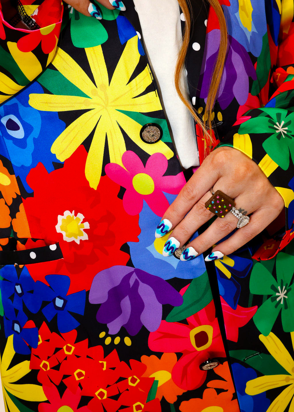 Model wearing a colorful floral jacket with polka dot collar, and matching shorts, a plain background, close up frontal view
