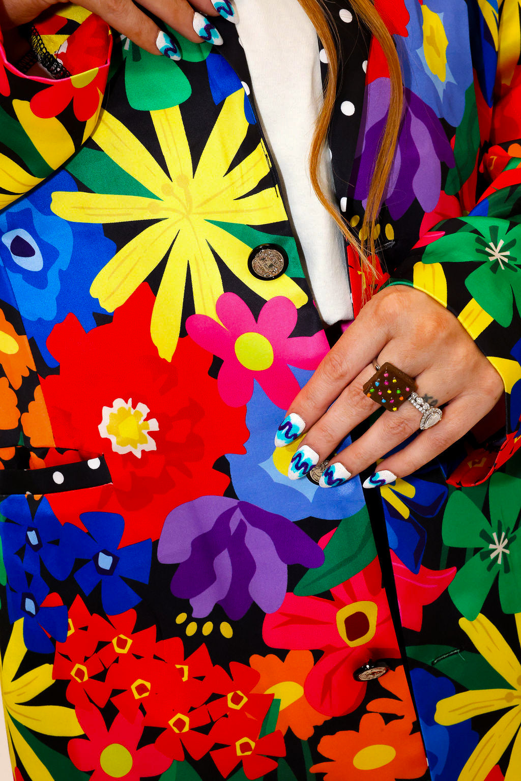 Model wearing a colorful floral jacket with polka dot collar, and matching shorts, a plain background, close up frontal view