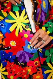 Model wearing a colorful floral jacket with polka dot collar, and matching shorts, a plain background, close up frontal view