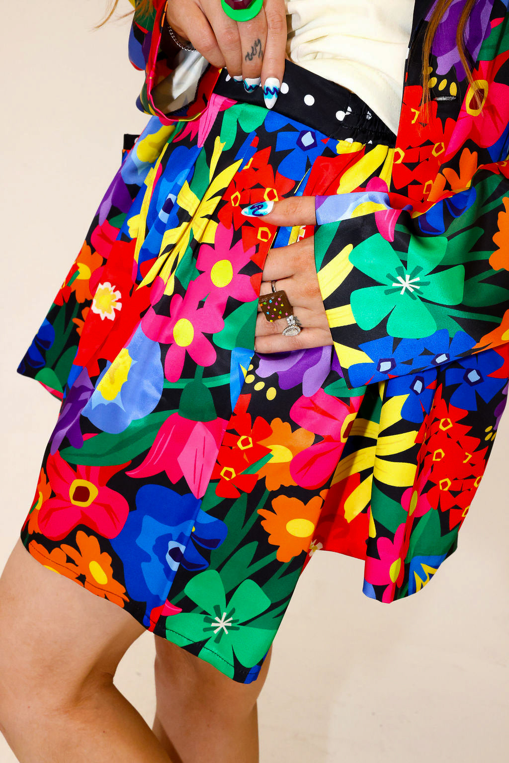 Colorful floral-patterned outfit with a focus on the shorts, hand in pocket, side view