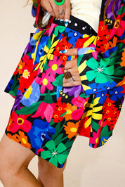 Colorful floral-patterned outfit with a focus on the shorts, hand in pocket, side view