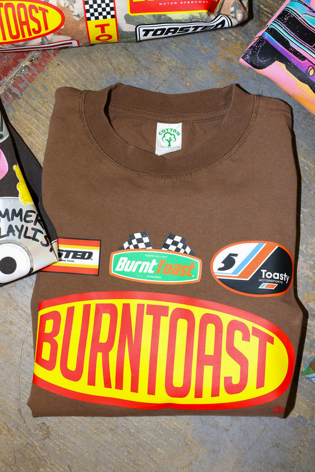 Folded brown t-shirt with 'Burnt Toast' logo on a textured surface
