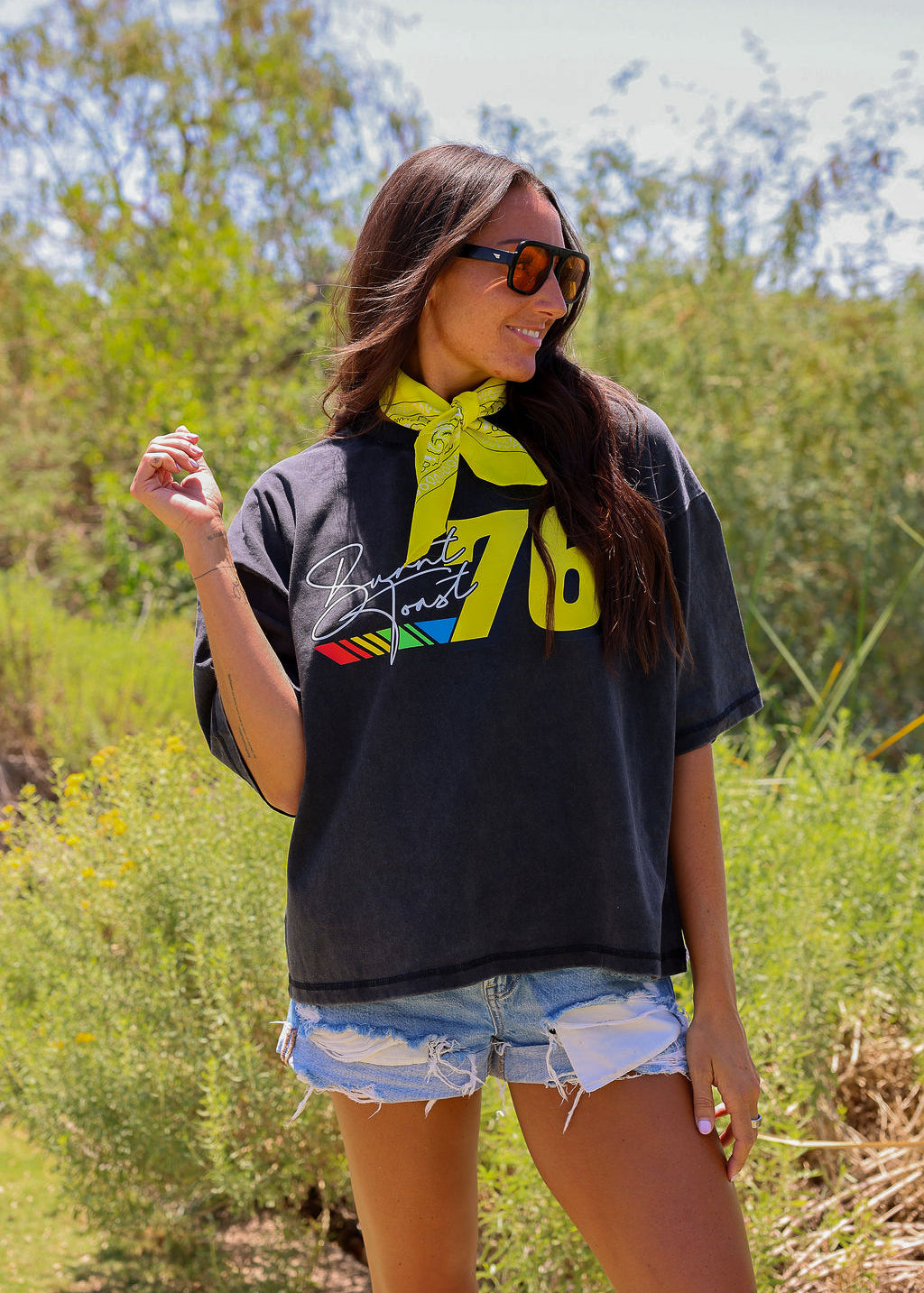 Woman wearing a black t-shirt with colorful design outdoors, frontal view