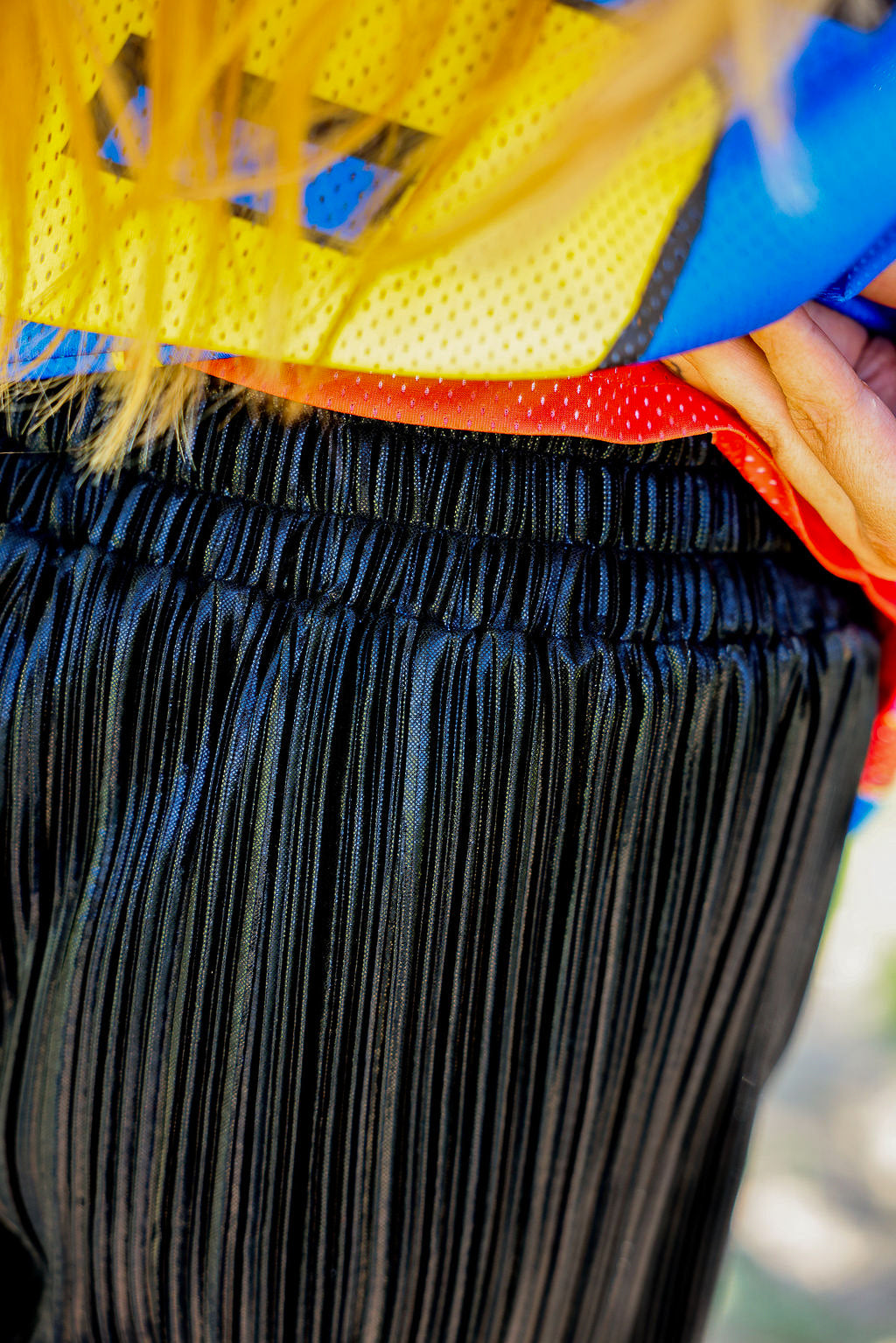 Close-up of waistband with a focus on black pleated shorts