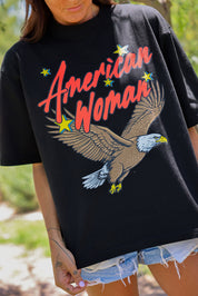 Person wearing a black short sleeve shirt with 'American Woman' and an eagle design, close up frontal view