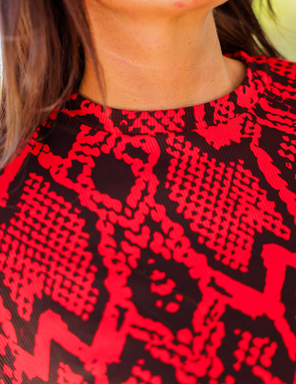 Close-up of neckline of a red and black patterned top worn by a person, frontal view