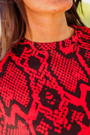 Close-up of neckline of a red and black patterned top worn by a person, frontal view