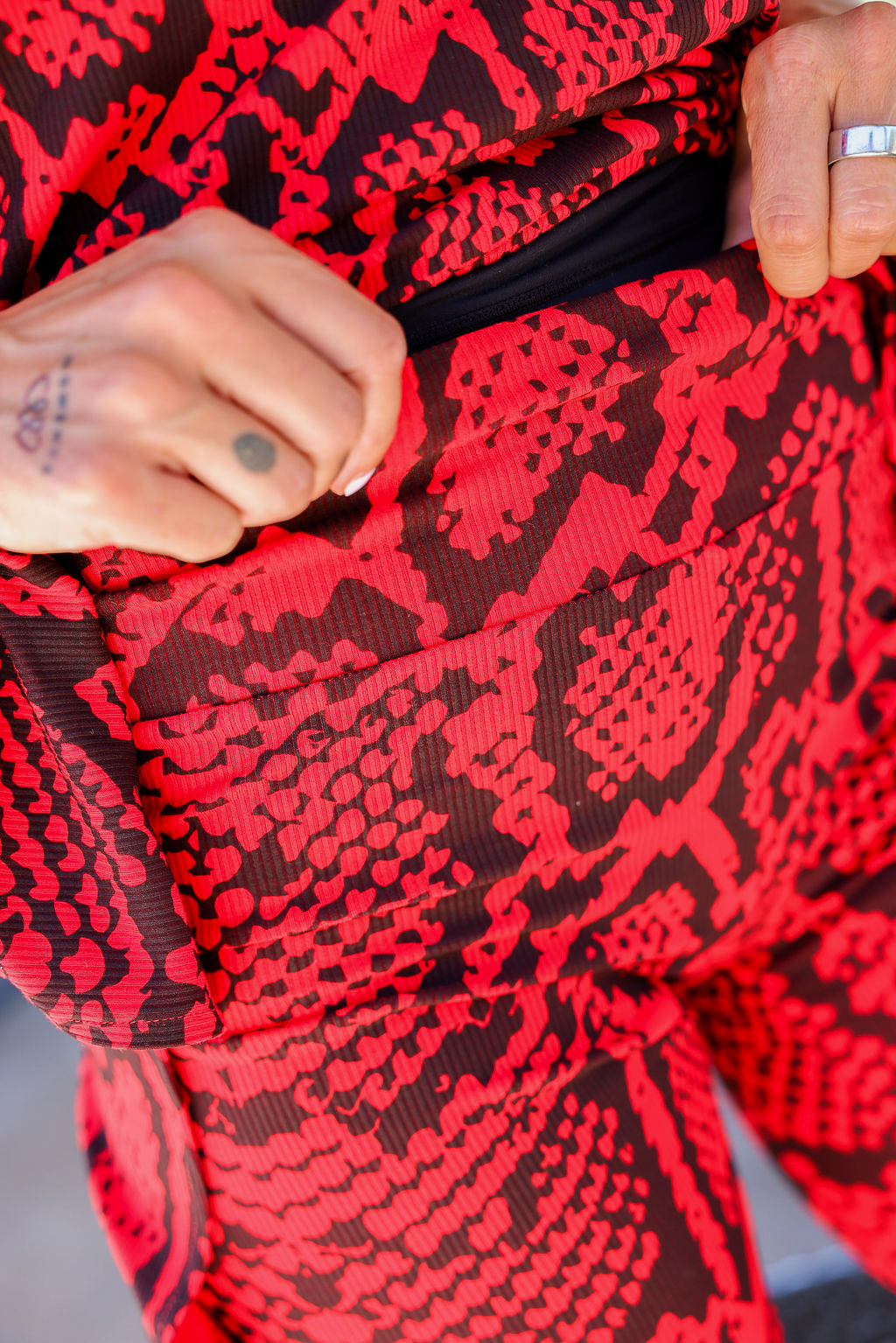 Close-up of a red and black patterned fabric with a hand holding the waistband