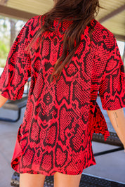 Person wearing a red and black snake skin patterned biker set with blurred background, back view