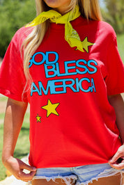 Model wearing a red short sleeve shirt with 'God Bless America' text and stars, outdoors, close up frontal view