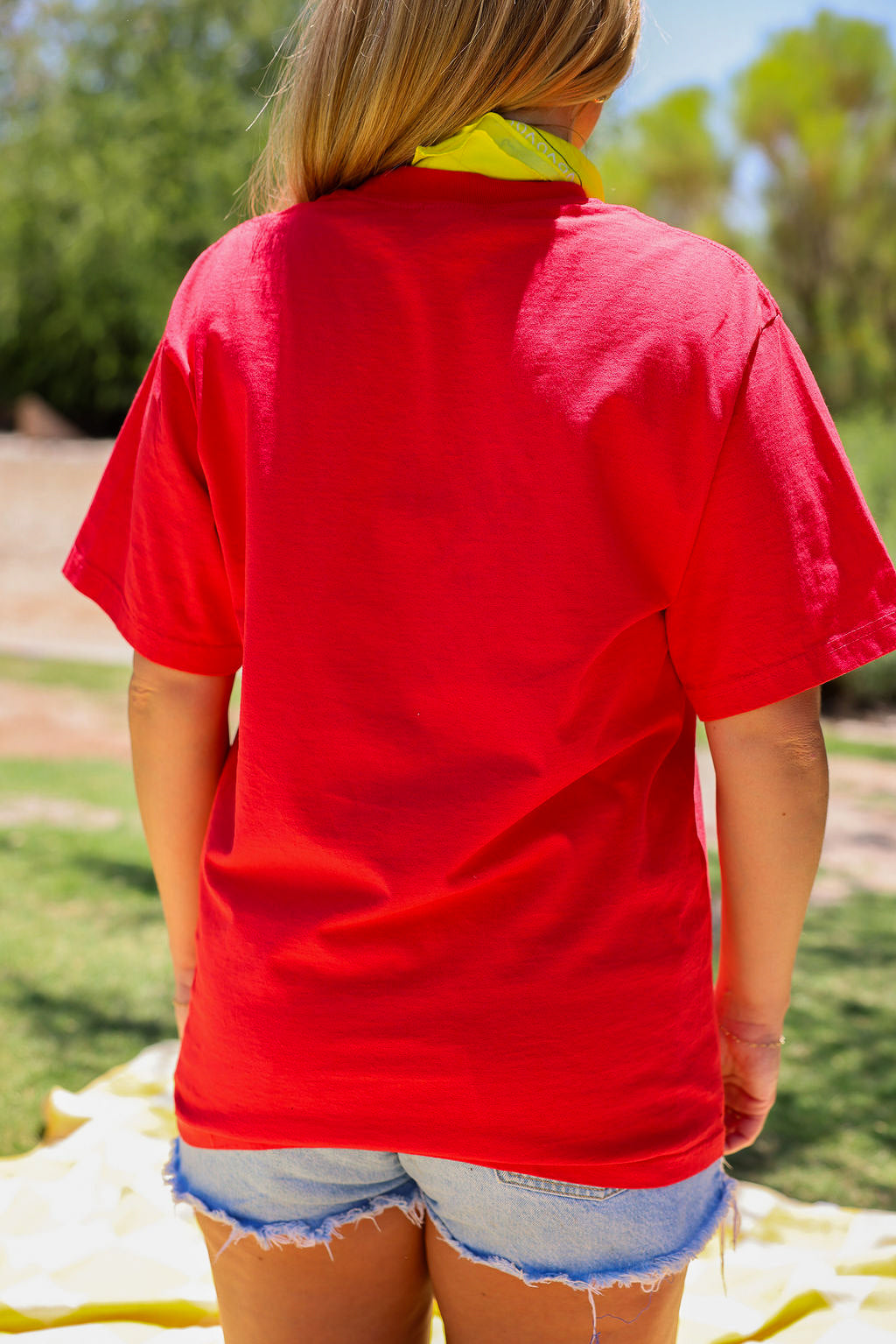 Model wearing a red short sleeve shirt outdoors, close up back view