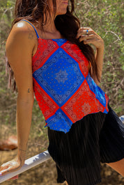 Model wearing a red and blue bandana patterned tank mesh top with black shorts outdoors, close up frontal view